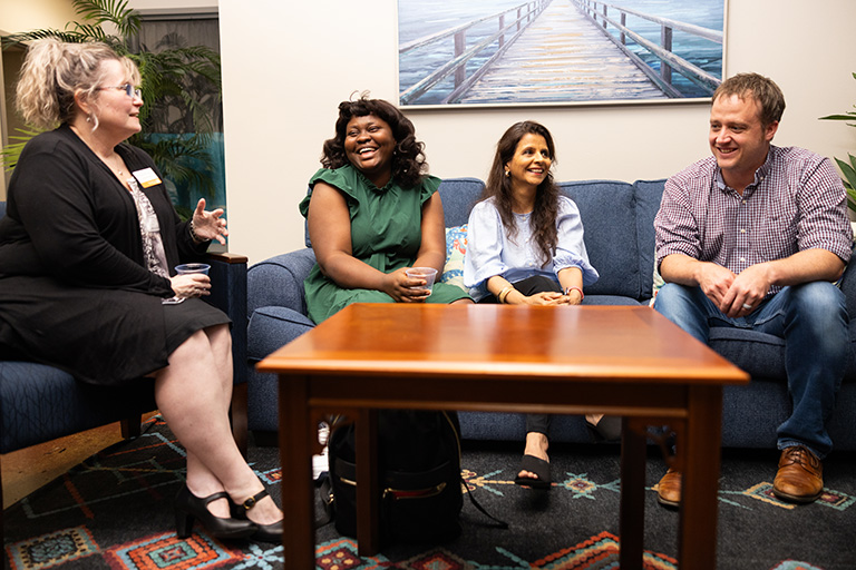 Four people sit on a couch discussing their work at the Cherokee Mills building.
