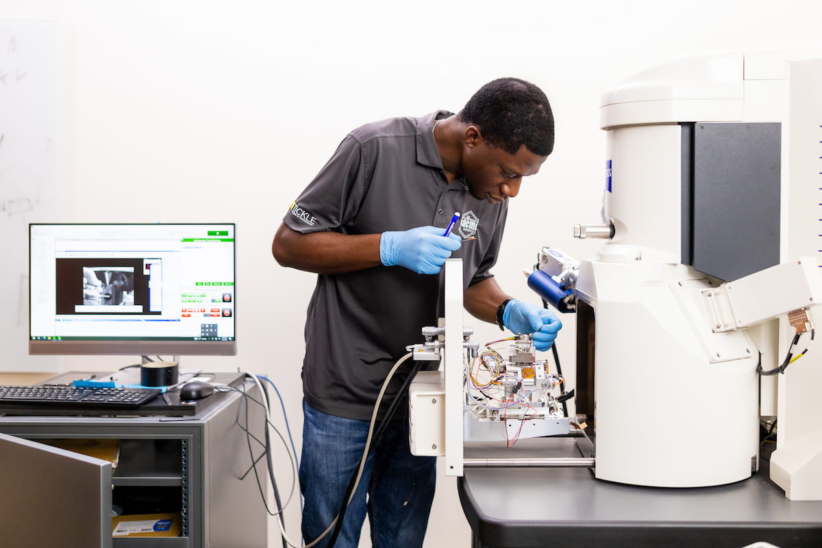 Technician operating scanning electron microscope in materials laboratory