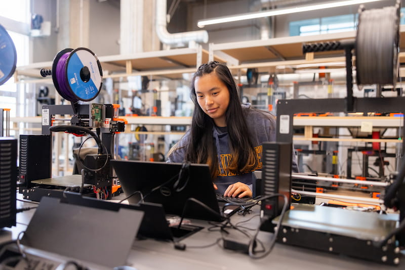Researcher at three-dimensional printer in materials science laboratory