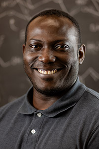 A man wearing a gray polo shirt, looks at the camera and smiles