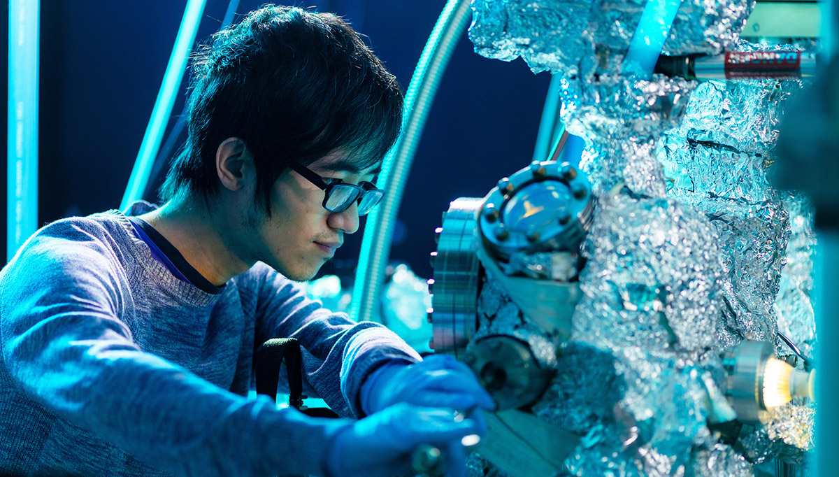 A student wearing glasses adjusts controls in the Molecular Beam Epitaxy Core Facility at the University of Tennessee, Knoxville.